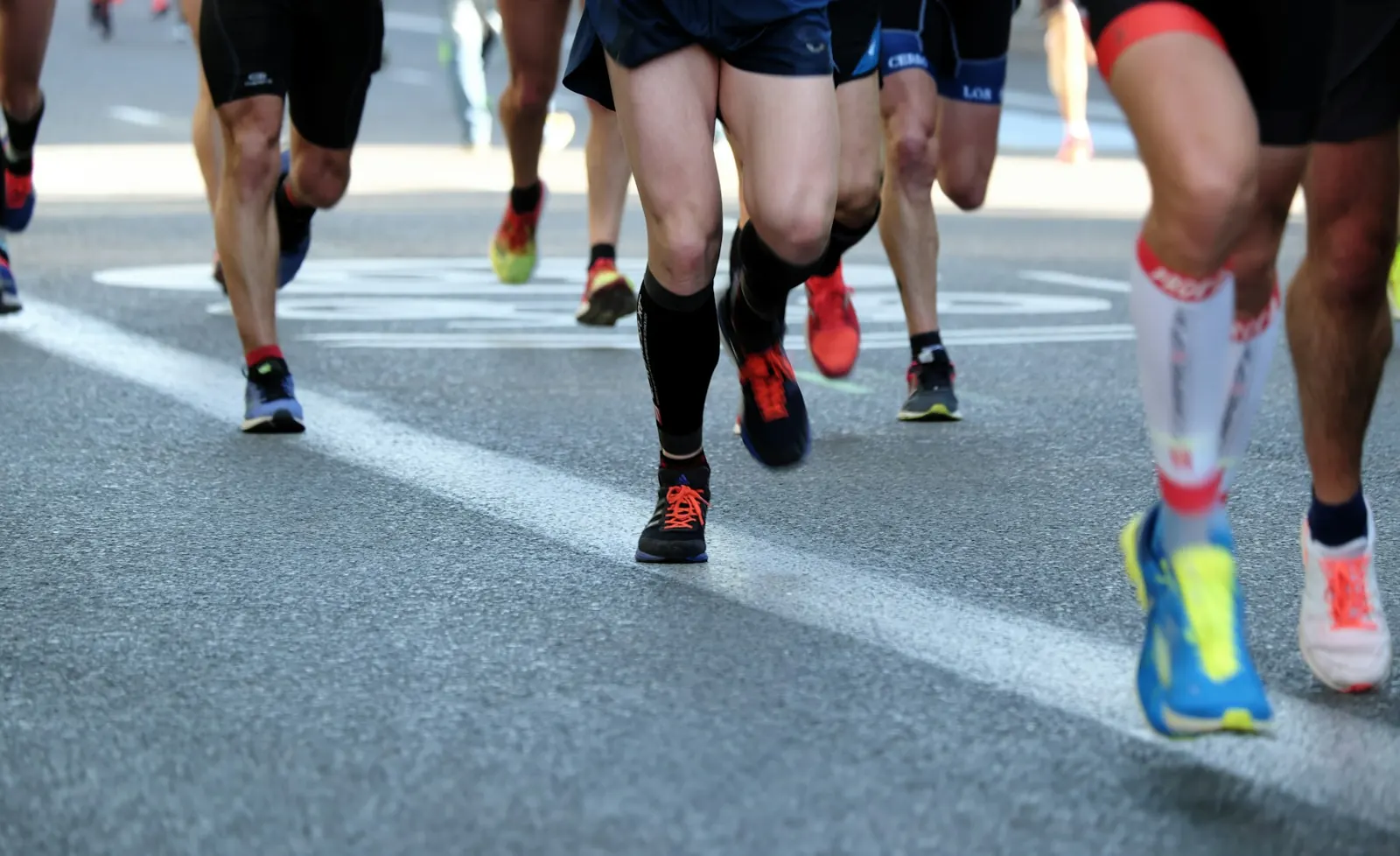 Group of runners' legs and shoes on a city road during a race