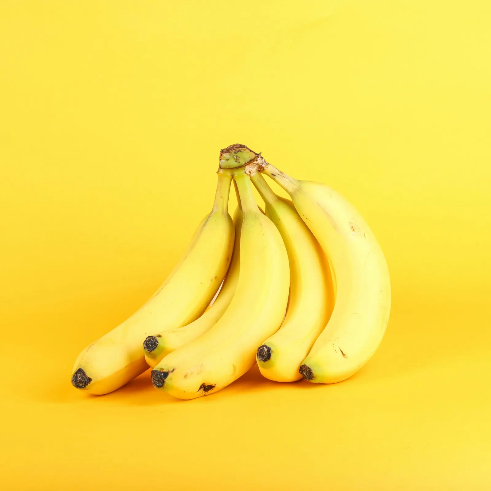 Bunch of ripe bananas on a yellow background