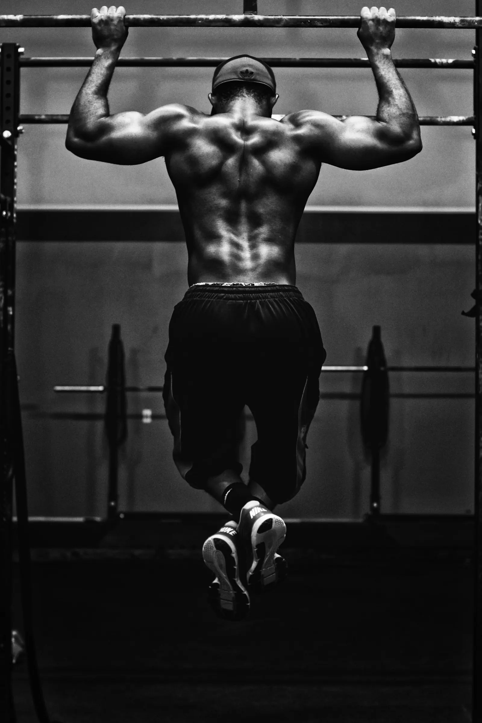 Athlete doing pull-ups in a dark gym, black and white photo