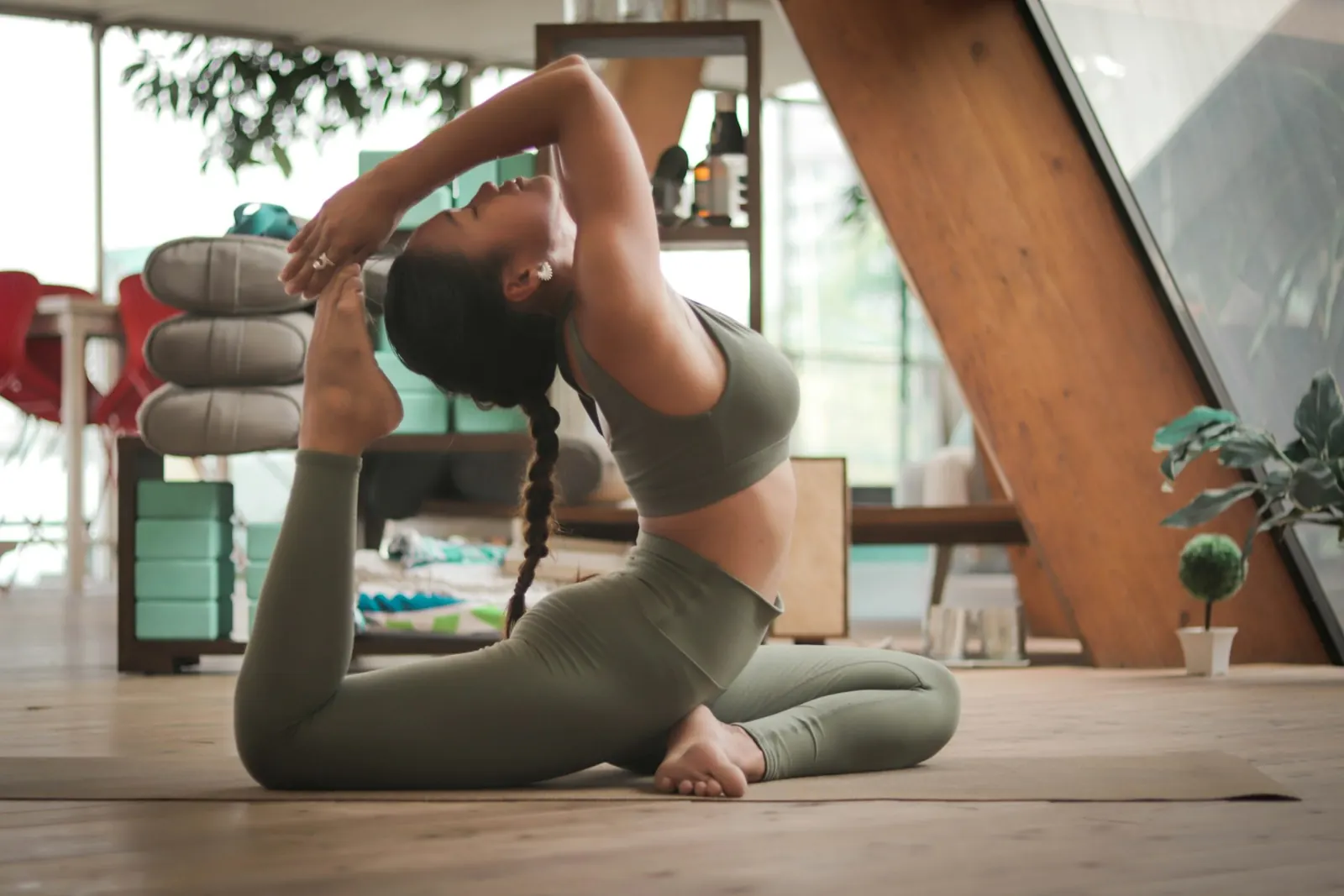 Woman doing a stretching pose on a yoga mat in a bright room