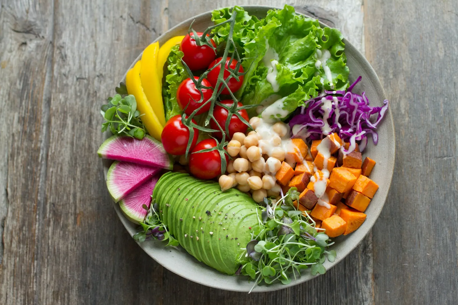 Colourful bowl of salad with chickpeas, avocado, tomatoes and sweet potato