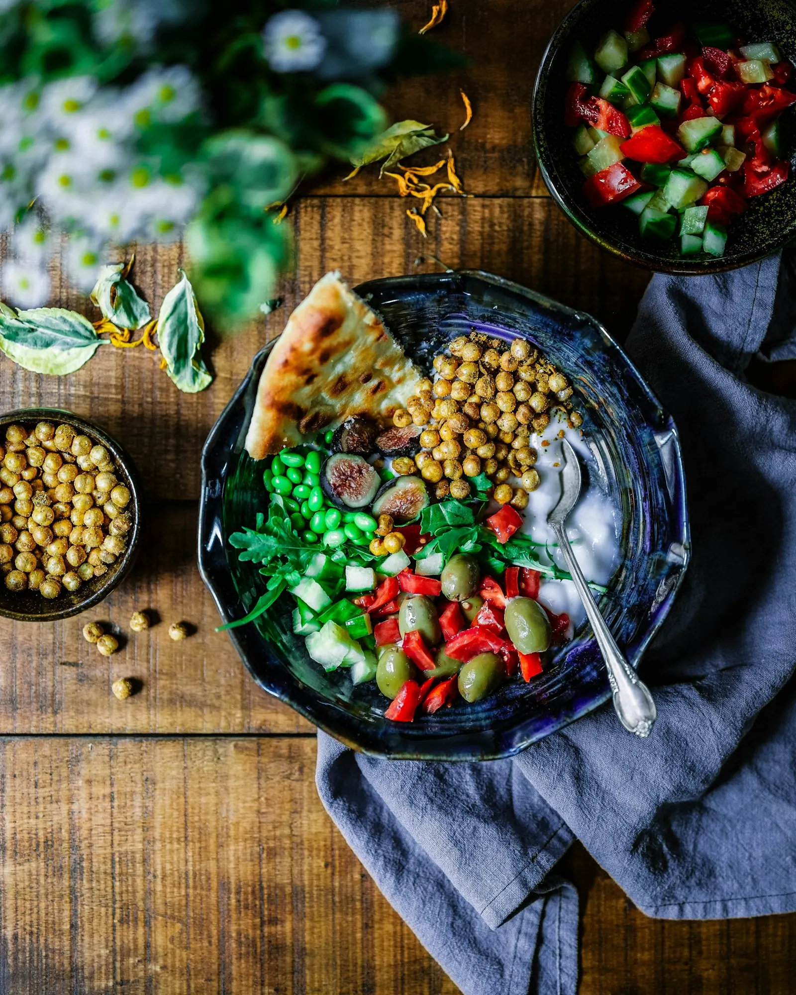 Bowl of chickpeas, tomatoes and greens on a dark table