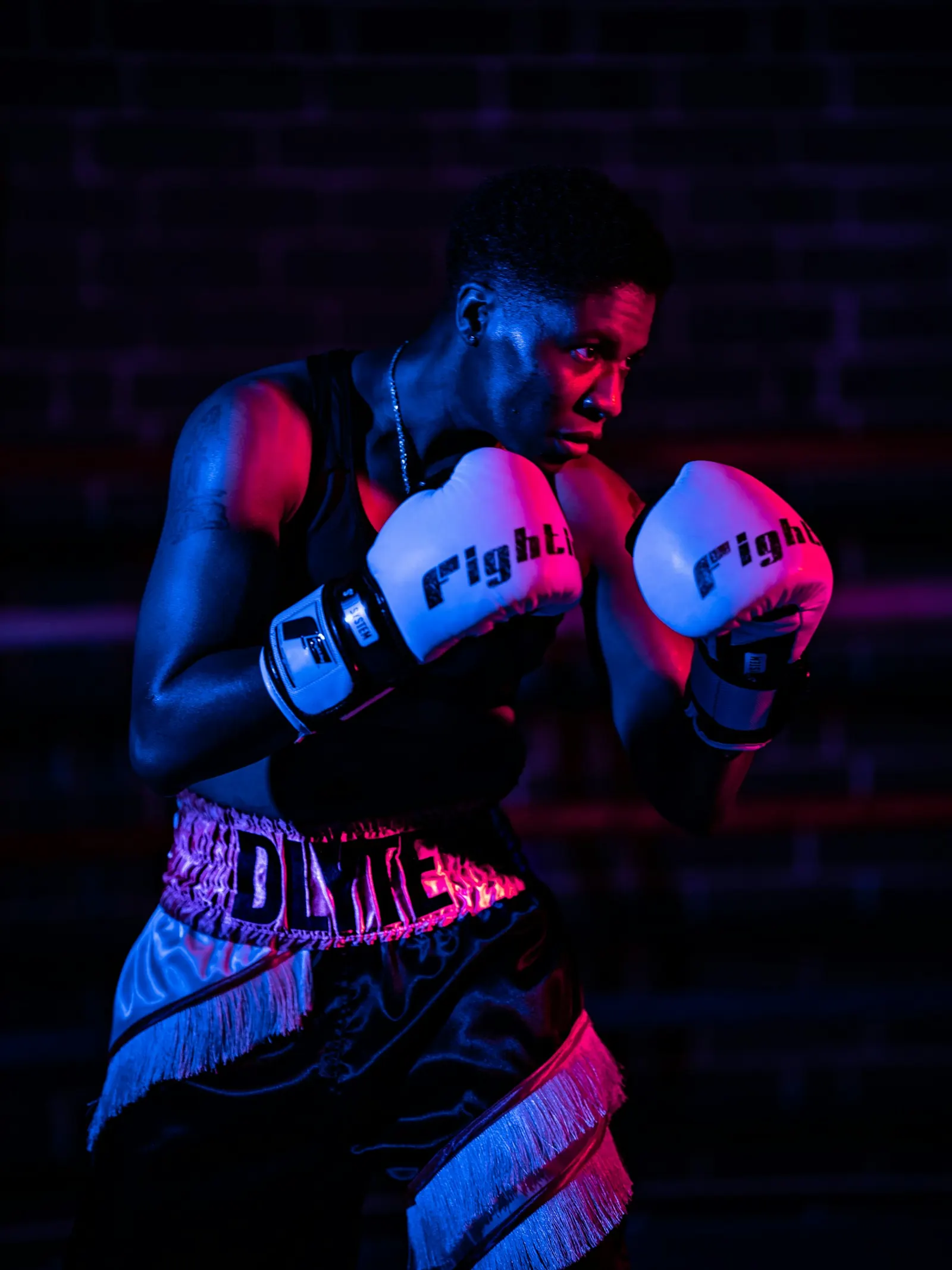 Boxer in gloves standing in blue and red light