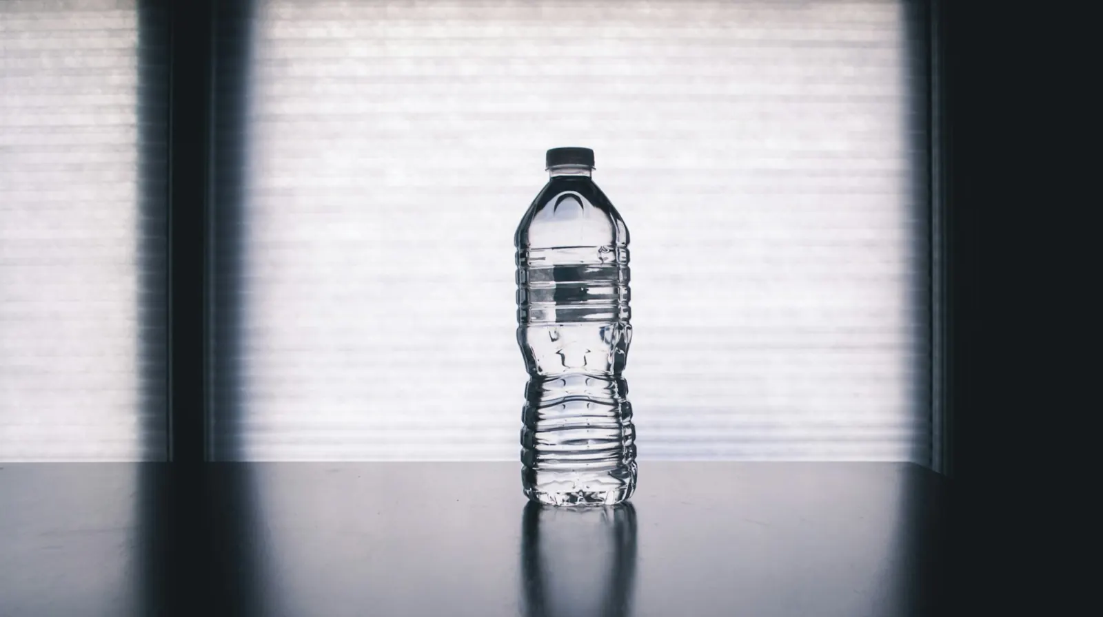 Plastic water bottle standing on a dark table