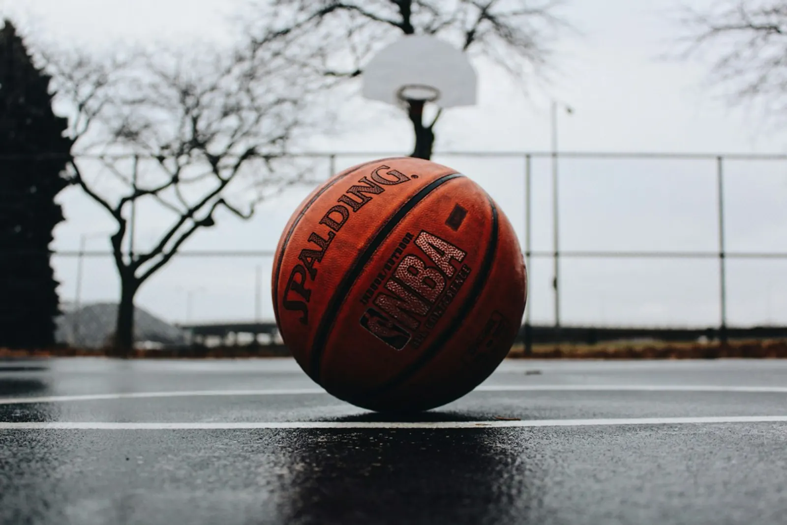 Basketball resting on an outdoor court with a hoop behind it