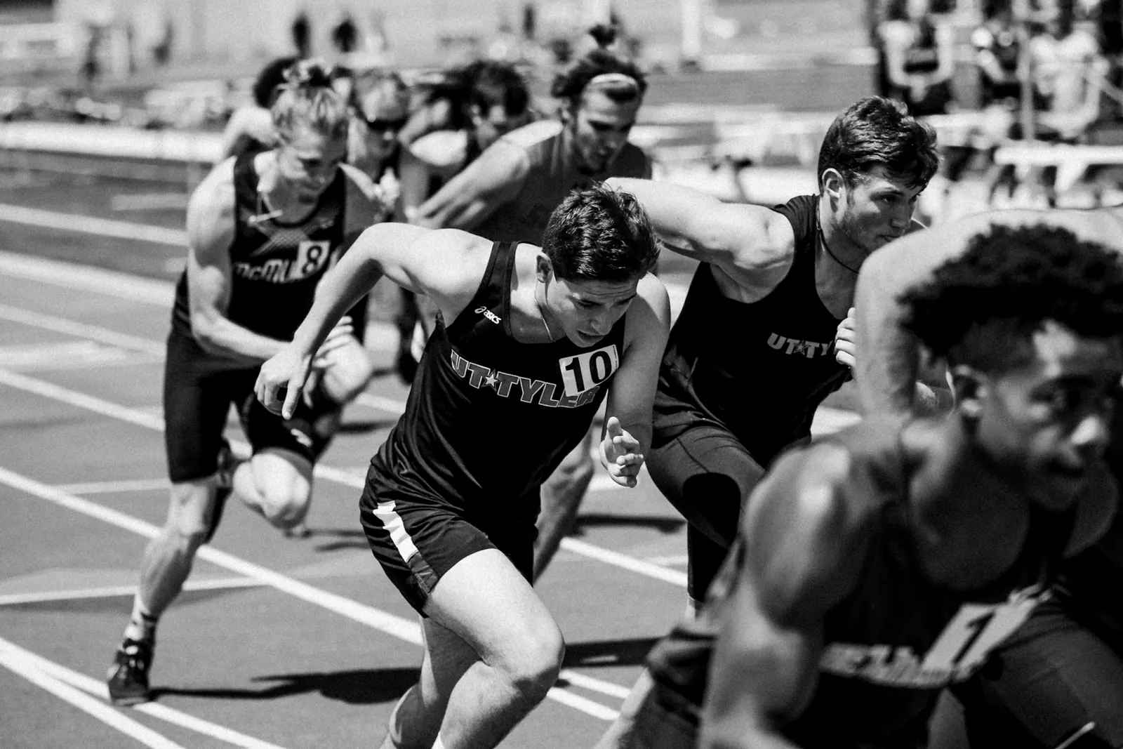 Sprinters exploding out of their starting positions, black and white photo