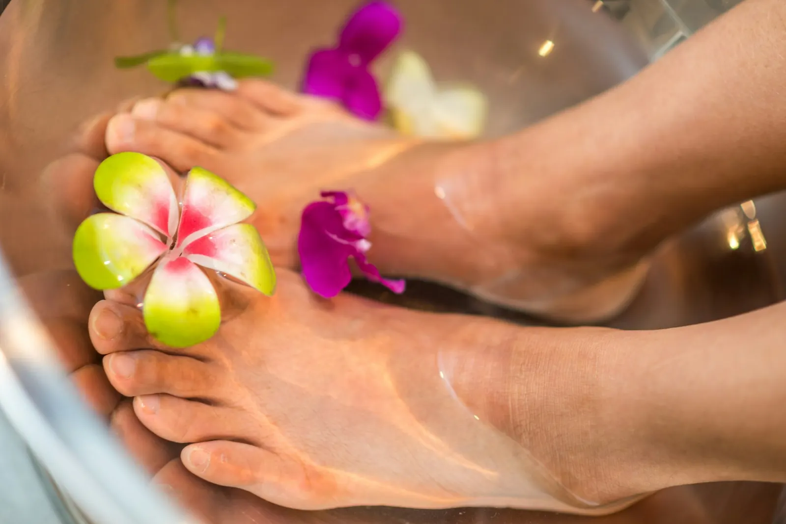 Feet resting in a basin of water with flowers