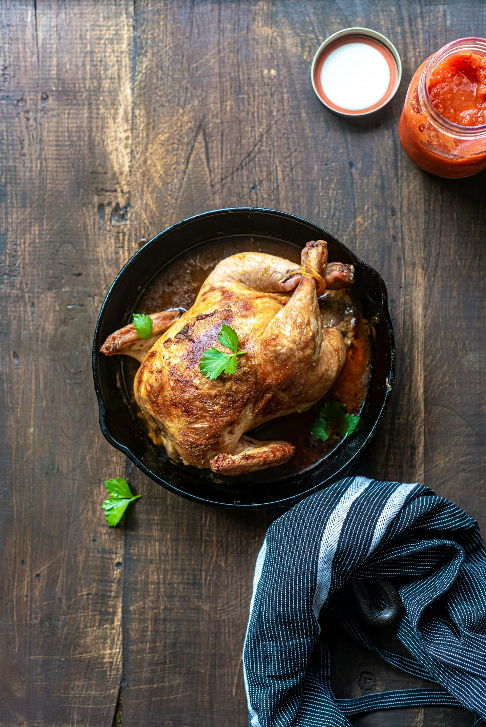 Roast chicken in a cast iron pan on a wooden table