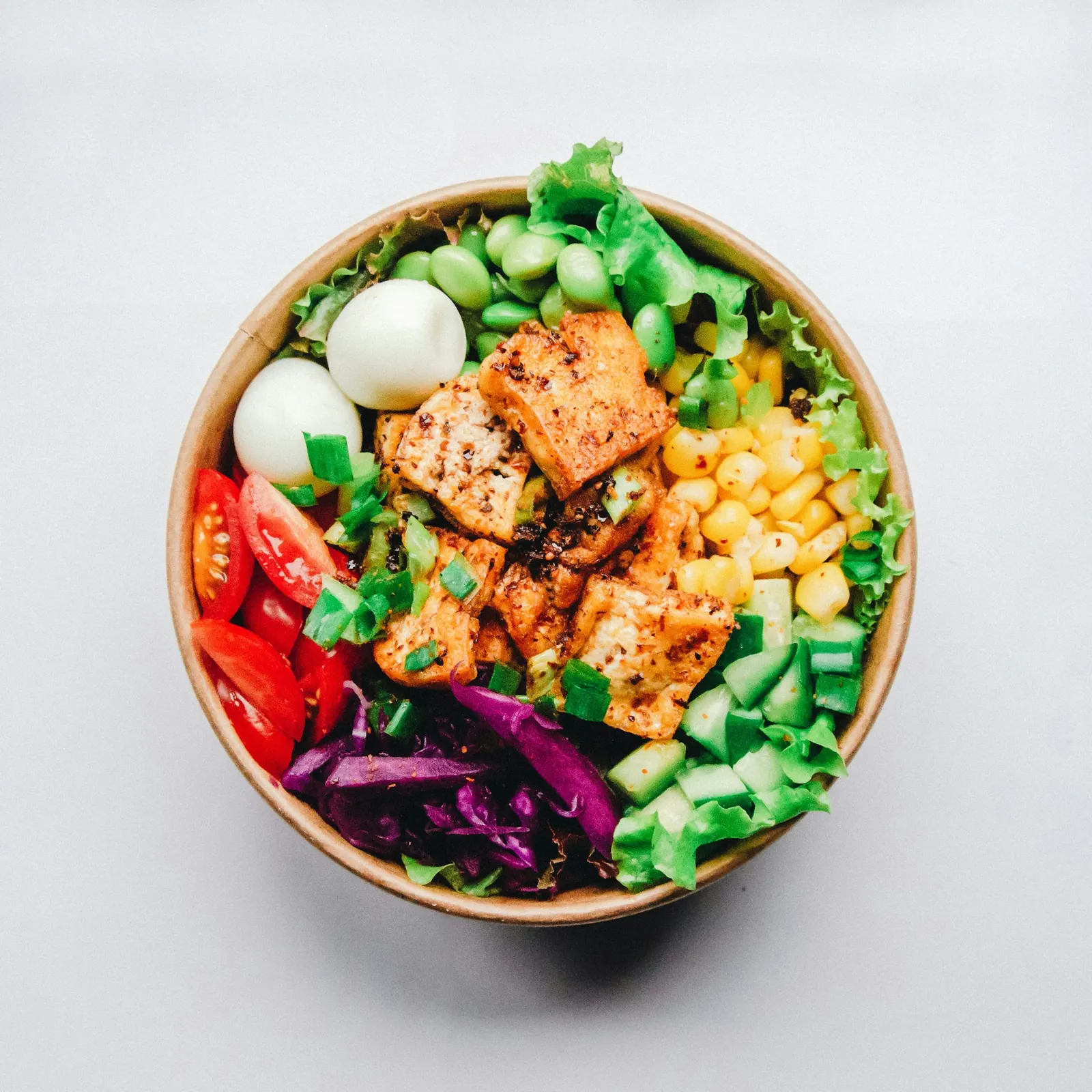 Bowl of salad with grilled tofu, egg, sweetcorn and vegetables