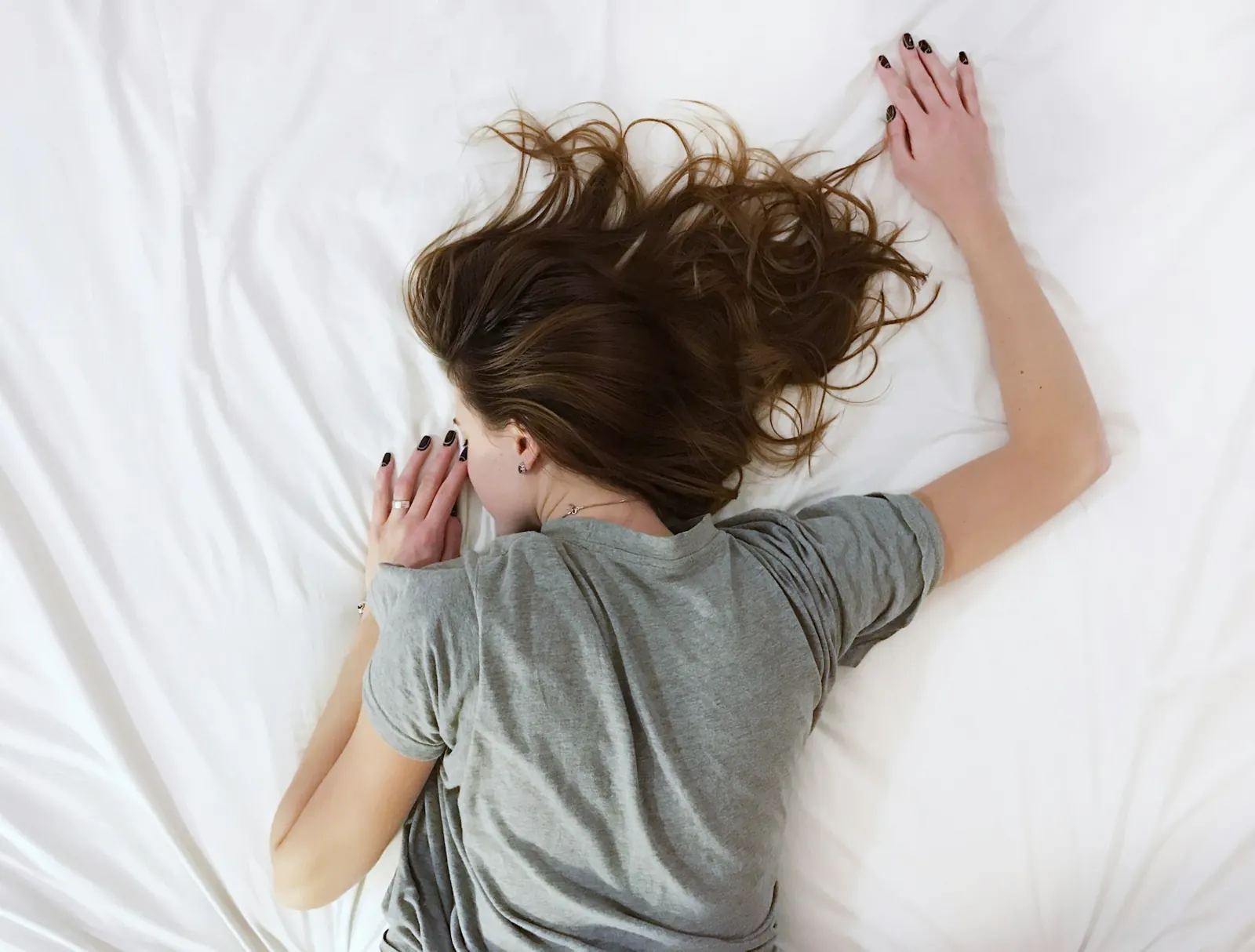 Woman lying face down asleep on a white bed