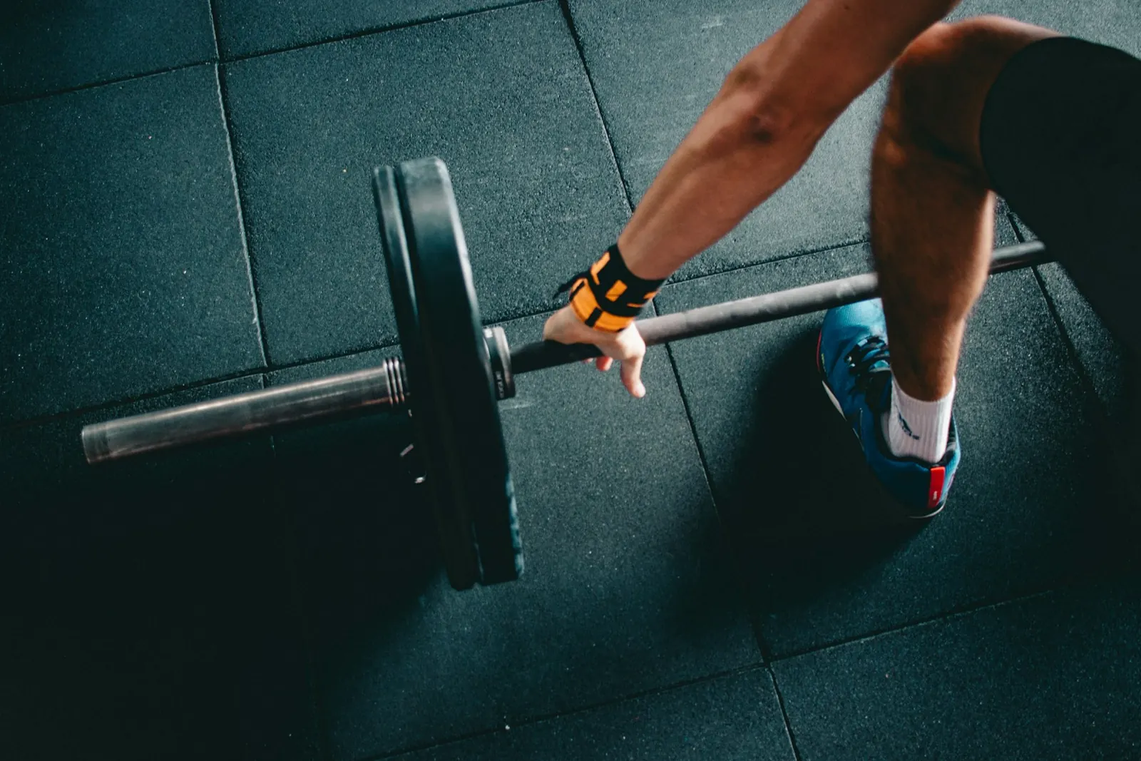 Athlete gripping a loaded barbell on a gym floor before a deadlift