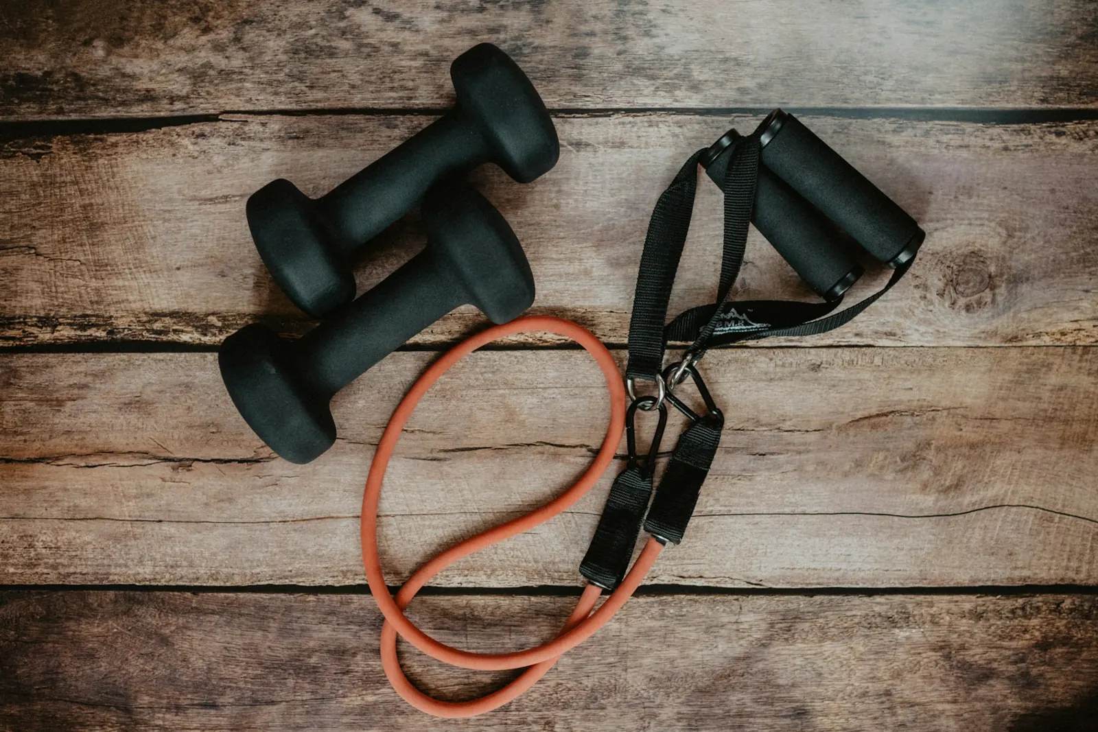 Pair of dumbbells and a resistance band on a wooden floor