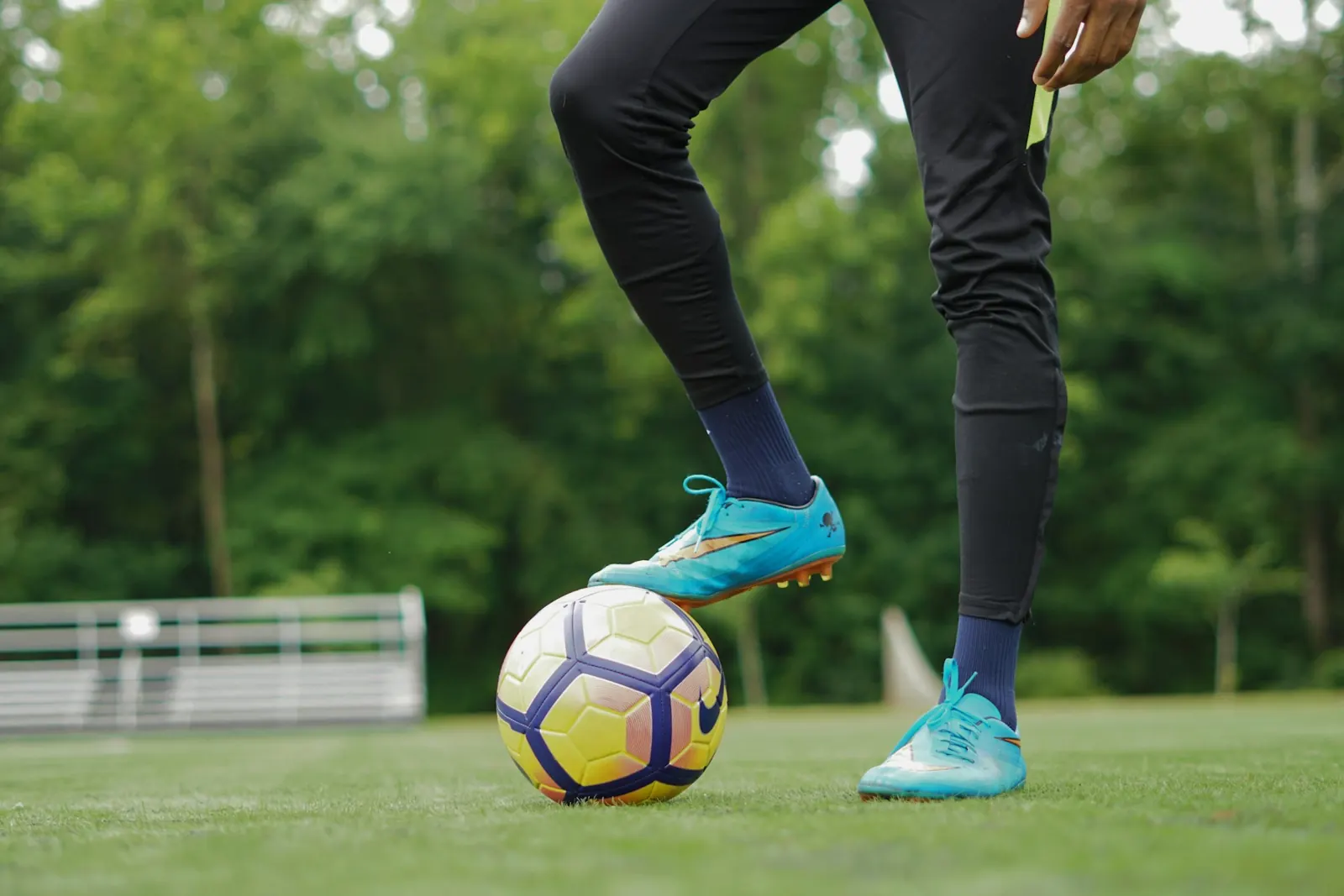 Footballer with a foot resting on the ball on a grass pitch