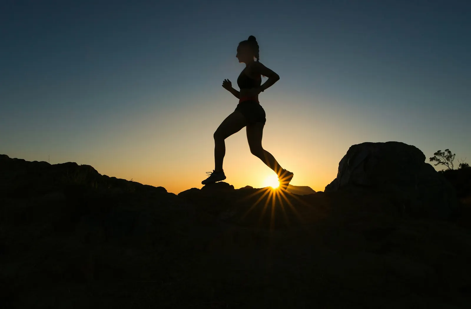 Silhouette of a runner on a ridge at sunrise